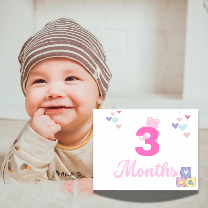 A baby milestone card leaning against a baby laying on her tummy. The sign says 3 months in complimentary shades of pink and features a pink teddy bear peaking out from the number 3 and 3 soft colored blocks in the