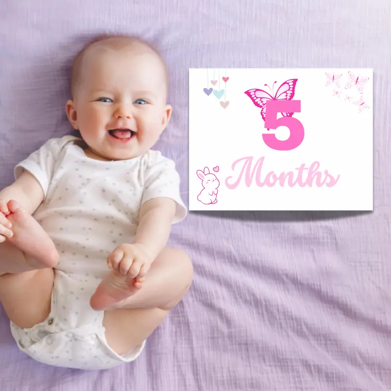A laughing baby laying on a purple sheet with a milestone sign beside her that says 5 months and features butterflies and a bunny. The card is in complimentary shades of pink.