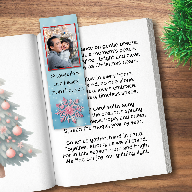 A Christmas bookmark with a father daughter photo on top a snowy sky laying in a book
