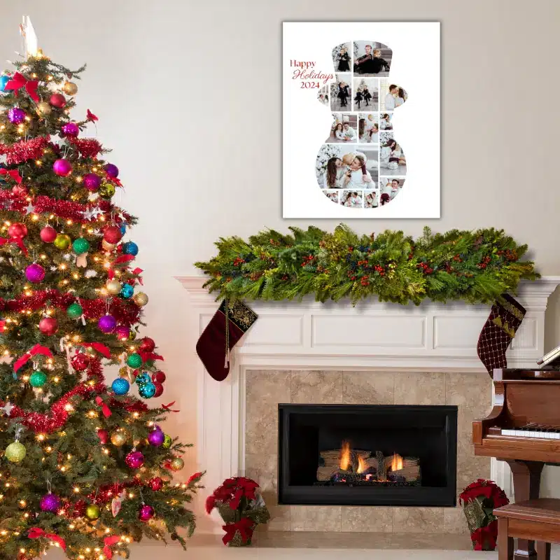 A winter photo collage in the shape of a snowman, filled with photos of a family celebrating Christmas hanging on the wall above a fireplace decorated for Christmas. There is a large Christmas tree to the left.