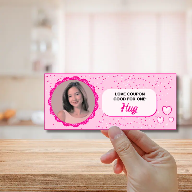 A Pink love coupon with a woman's loving photo on it. Love coupon is good for one hug and has a variety of shades of pink hearts