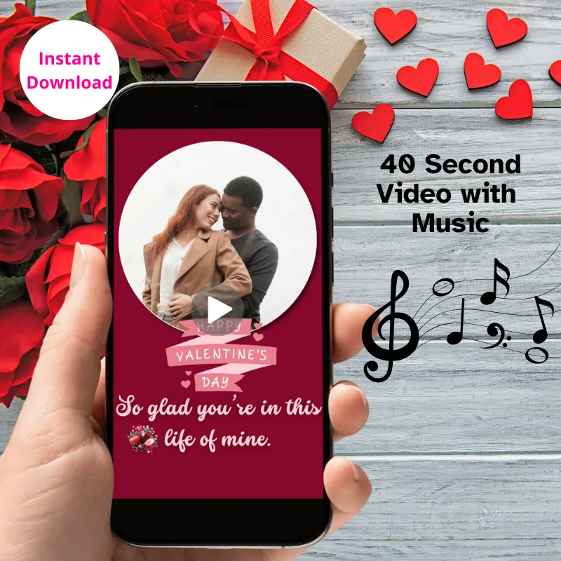 A hand holding a phone with a Valentine's Day Animated Card playing on it with music in front of a table with valentine decorations on it.